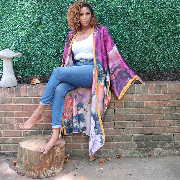 A model poses in a purple kimono cardigan featuring delicate floral patterns and a golden yellow trim, showcasing its fully lined, sophisticated style.