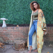 The model wears a golden yellow kimono robe with subtle olive branches, creating a soft and elegant design perfect for a refined, nature-inspired look.