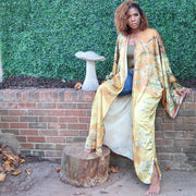 A model showcases a golden yellow  Japanese kimono robe adorned with subtle olive branch patterns, blending luxurious color with a subtle, natural design.