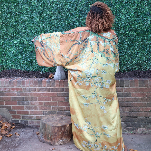 The model wears a golden yellow kimono robe with subtle olive branches, creating a soft and elegant design perfect for a refined, nature-inspired look.