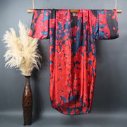 Red flower petals on blue background decorate the front of long kimono robe hanging on a bamboo bar