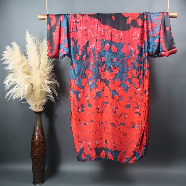a bamboo rod hung from the ceiling displays a long kimono robe designed with red flower petal on a blue background