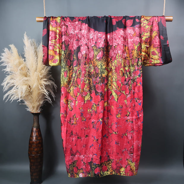 floor length kimono robe pictured from the back hanging on a bamboo display rod pink black and gold